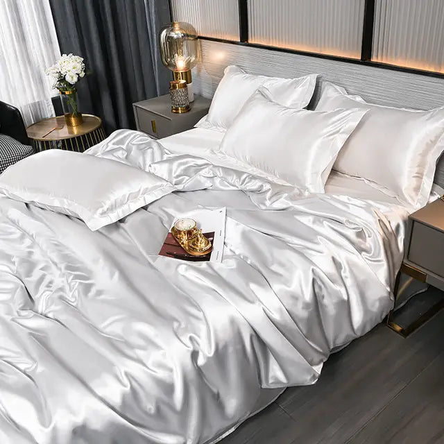 Luxuriöses weißes Seidensatin-Bettwäsche-Set mit Kissen und Decke im modernen Schlafzimmer.
