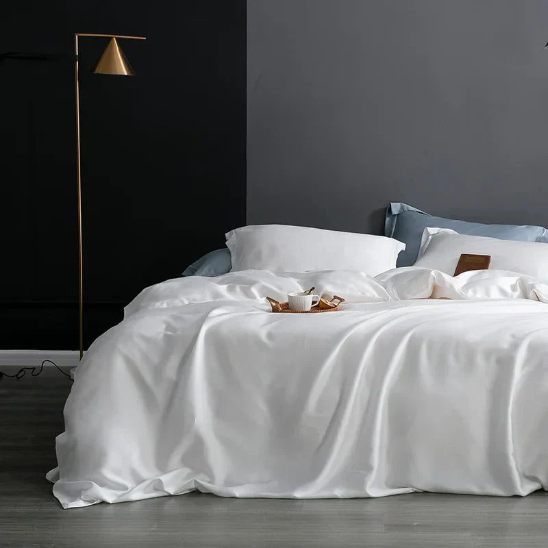 Luxuriöses weißes Seidenbettwäsche-Set auf modernem Doppelbett mit Nachttischlampe.