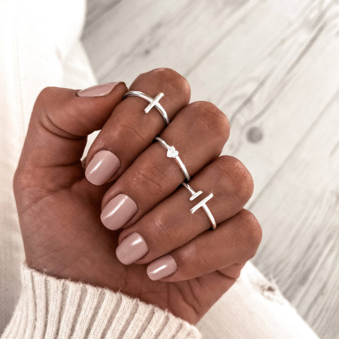 Silberne Magnetringe mit Kreuzdesign auf Hand, minimalistischer Schmuck, stilvoll, modern.