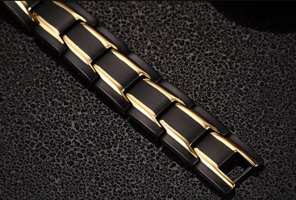 Schwarzes und goldenes magnetisches Armband aus Edelstahl auf strukturiertem Hintergrund.