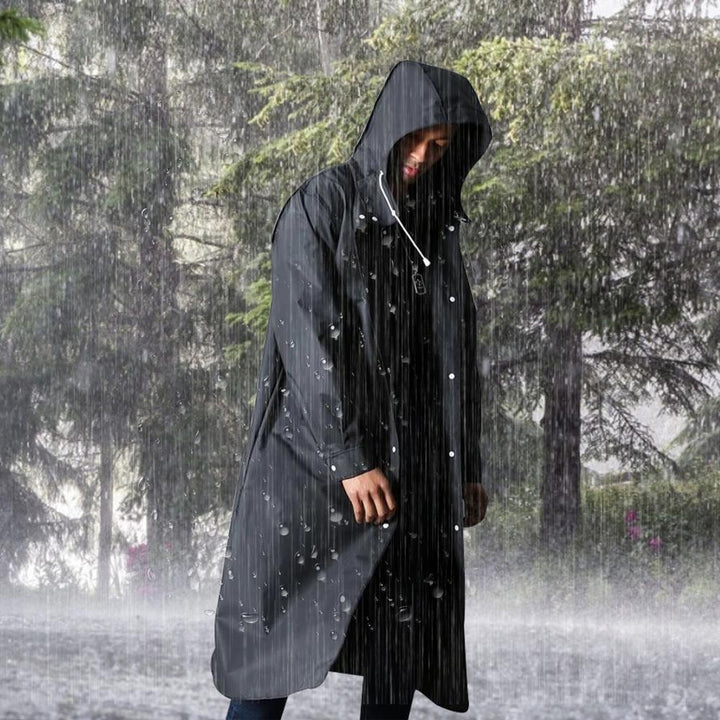 Mann in schwarzem Regenmantel mit Kapuze im Regenwald, wasserdicht, Outdoor-Bekleidung.