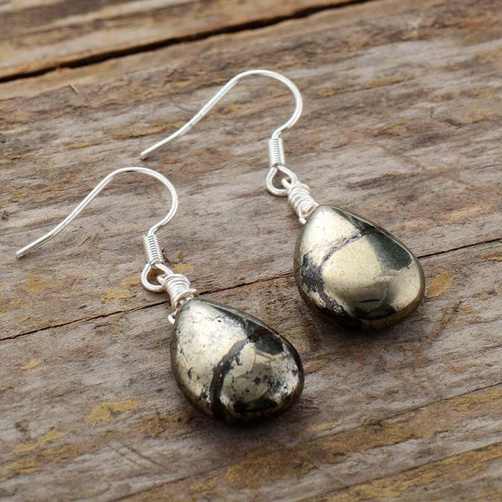 Teardrop-Ohrringe aus Pyrit, eleganter Schmuck für Damen, Geschenkidee, auf Holzoberfläche.