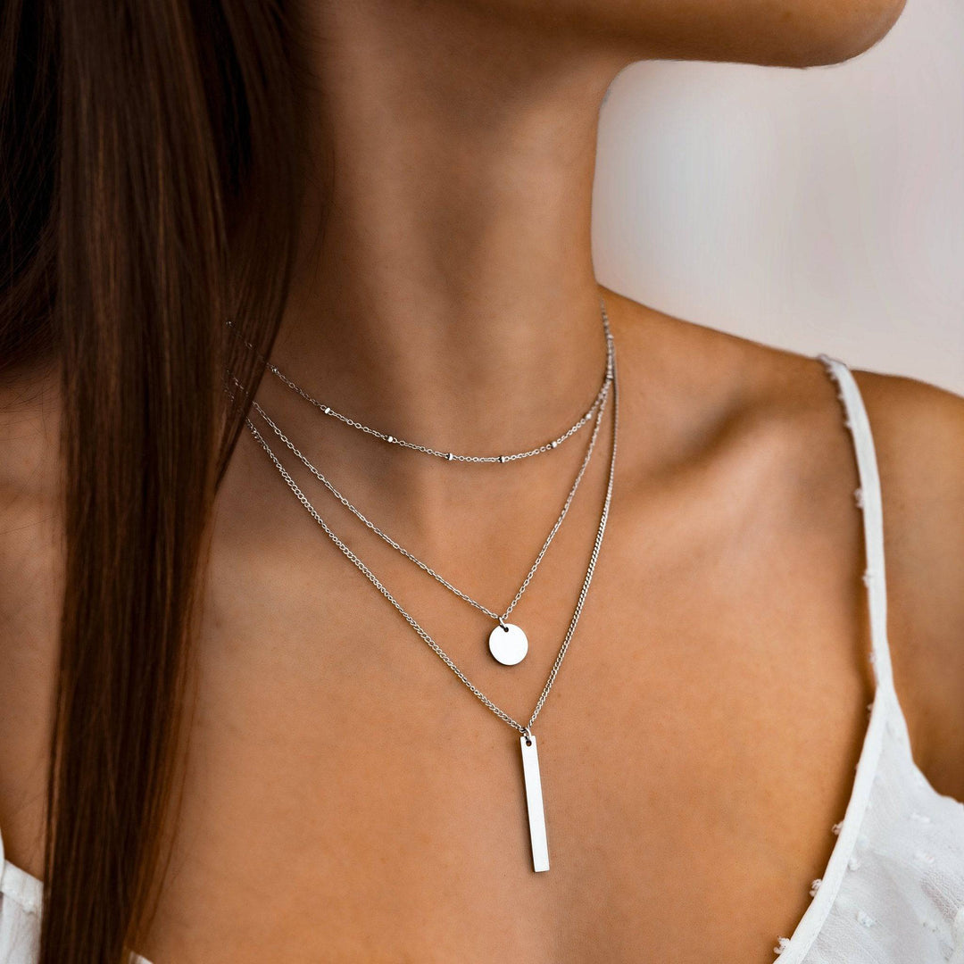 Frau trägt silberne Halskette mit Anhänger, minimalistischer Schmuck, elegantes Design.