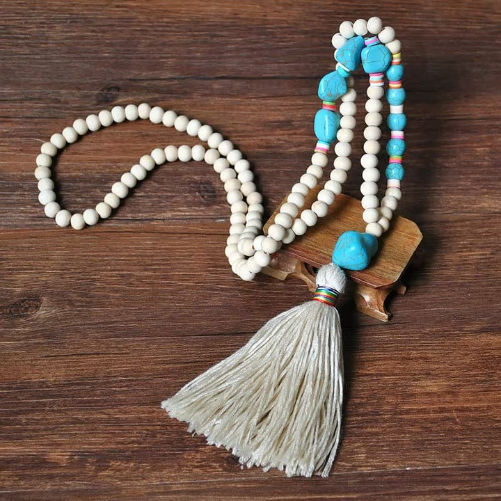 Holzperlenkette mit blauen Steinen und Quaste, handgefertigt, Boho-Schmuck, auf Holztisch.