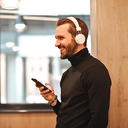 Mann mit weißen Kopfhörern und Smartphone, lächelnd, schwarzer Rollkragenpullover, modern.