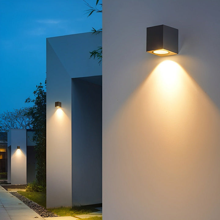 Kostkové svítidlo na zdi svítí dolů, další lampy podél domu a chodníku 6