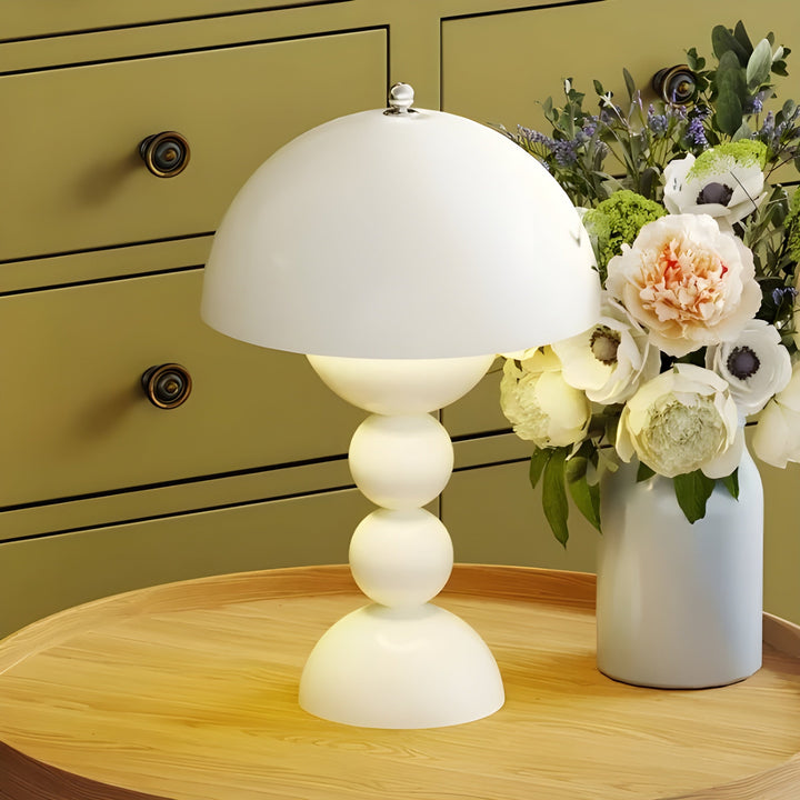Weiße Tischlampe mit Kugelfuß, skandinavisches Design, neben Blumenstrauß auf Holztisch.