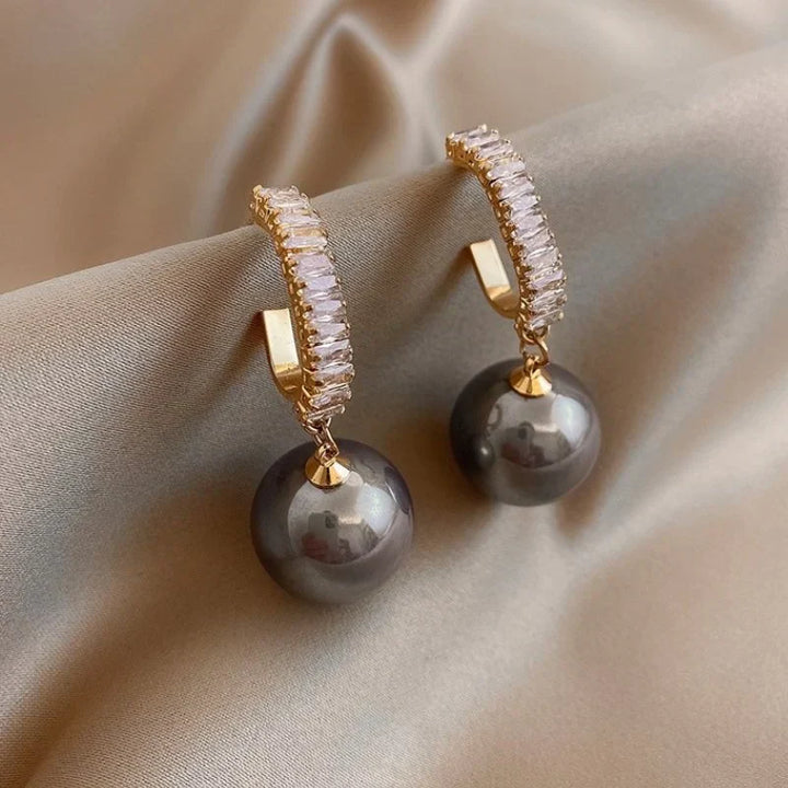 Goldene Ohrringe mit schwarzen Perlen und Kristallen, eleganter Schmuck, luxuriöses Design.
