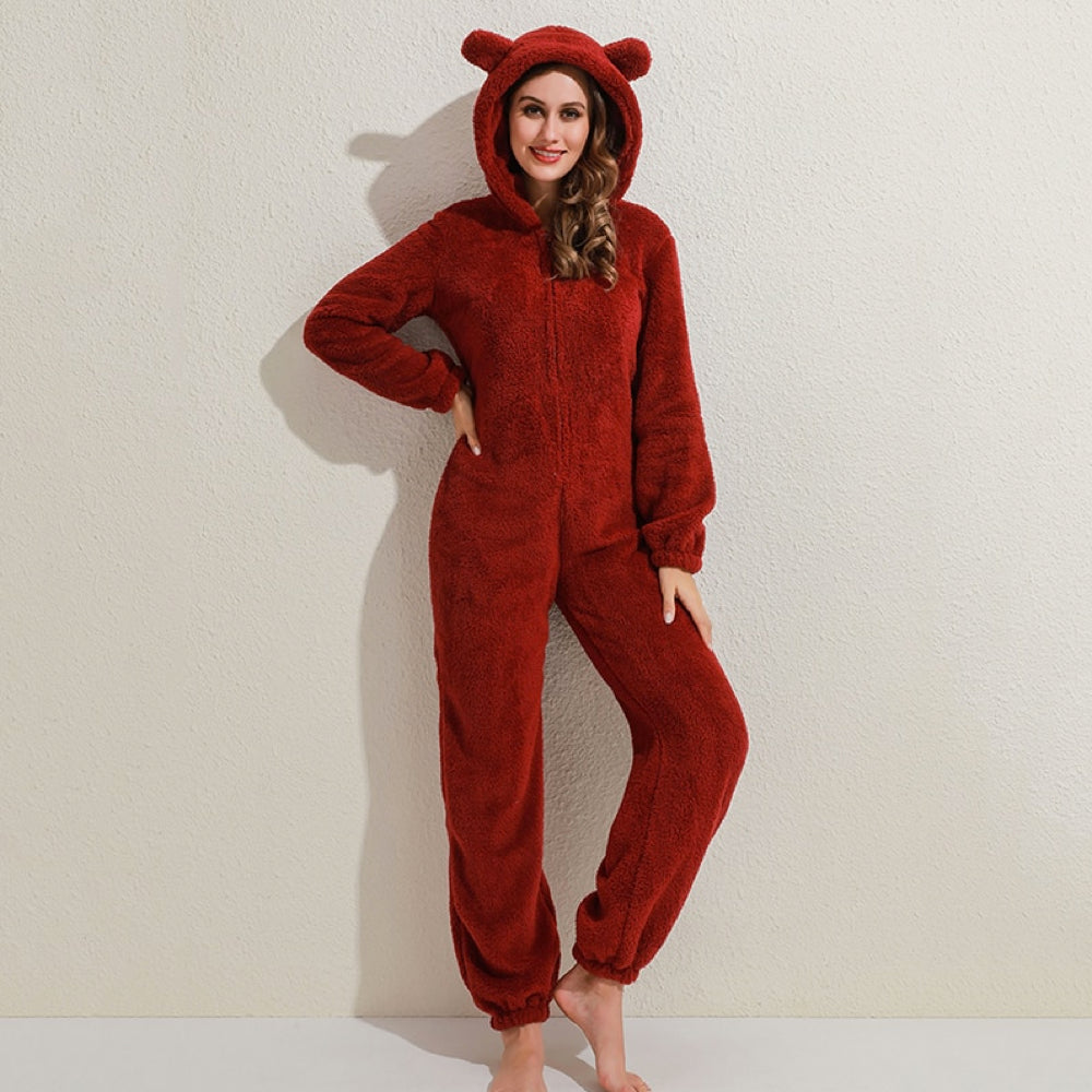 Frau in rotem Plüsch-Onesie mit Kapuze und Bärenohren, gemütliche Nachtwäsche, Damenmode.