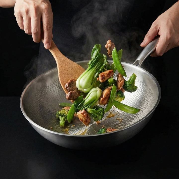 Kuchař míchá dřevěnou stěrkou v woku pak choi, brokolici, hrášek a maso, druhou rukou drží rukojeť, stoupá pára. 7