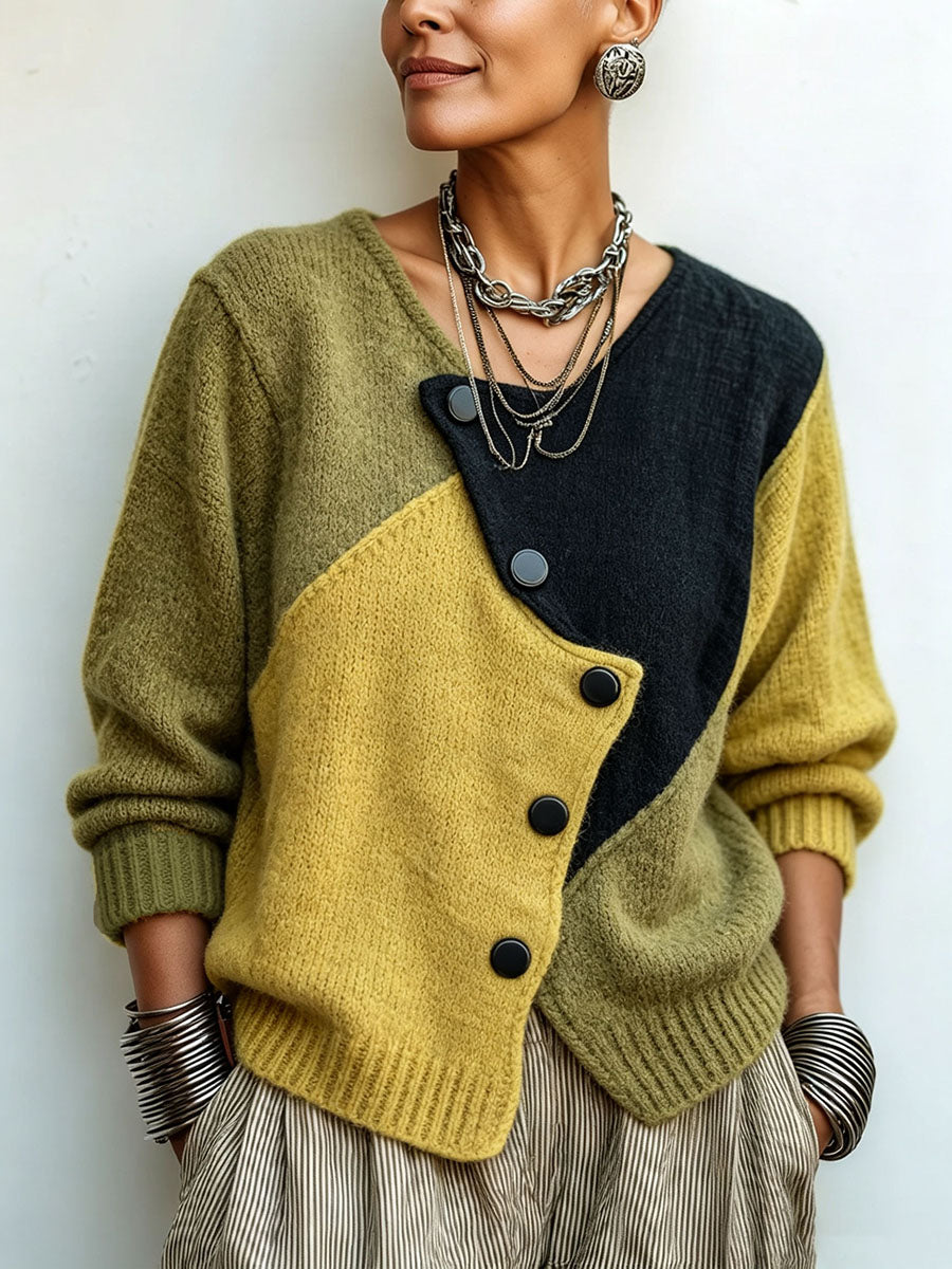 Detailní záběr na modelku ve svetru s šikmým zapínáním na černé knoflíky, olivovými, hořčicovými a černými poli, se stříbrnými řetězy a náramky. 1