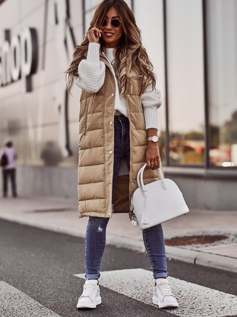 Frau in beige, knielanger Steppweste, weiße Sneakers, Jeans, weiße Handtasche, Straße, Herbstmode.