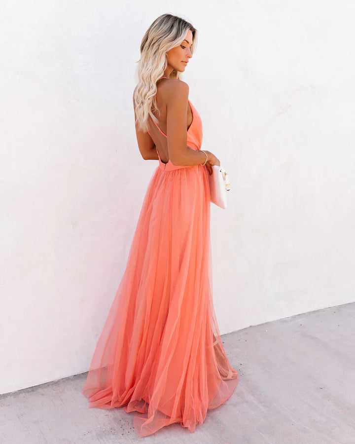 Frau in apricotfarbenem Maxikleid aus Tüll, elegantes Abendkleid, Sommermode, Rückenansicht.