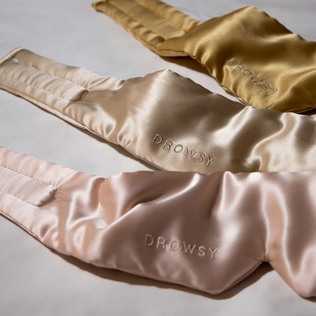 Drei Drowsy Schlafmasken aus Maulbeerseide in Gold, Beige und Rosa auf weißem Hintergrund.