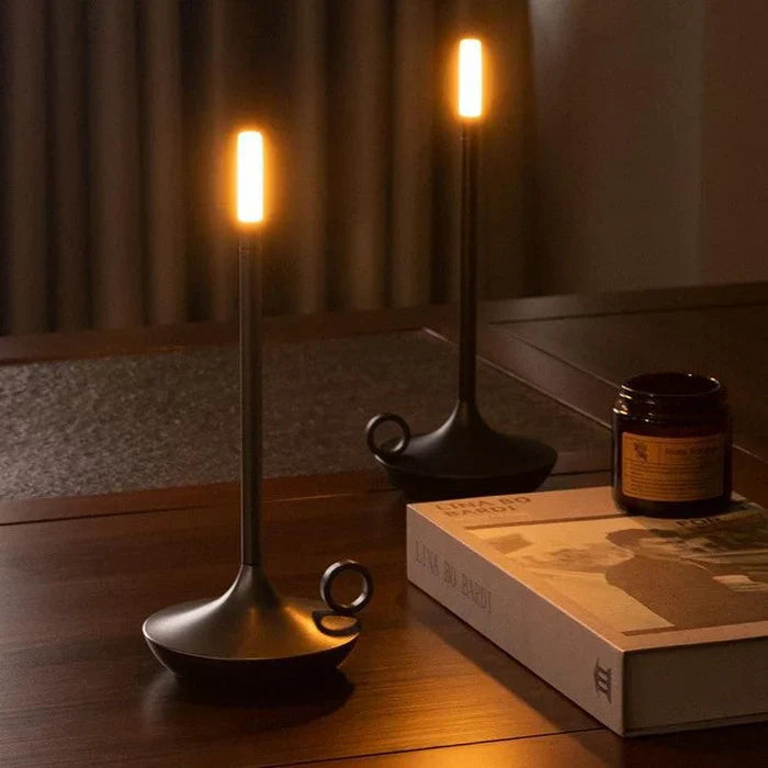 Moderne schwarze LED-Kerzenleuchte auf Holztisch, warmes Licht, dekorative Beleuchtung.