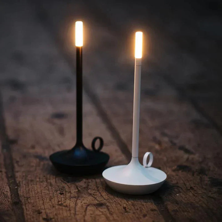 Zwei moderne LED-Kerzenleuchter, schwarz und weiß, auf Holzboden, minimalistisch, stilvoll.