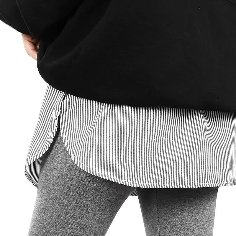 Schwarz-weiß gestreiftes Hemd unter schwarzem Pullover, graue Leggings, modischer Lagenlook.