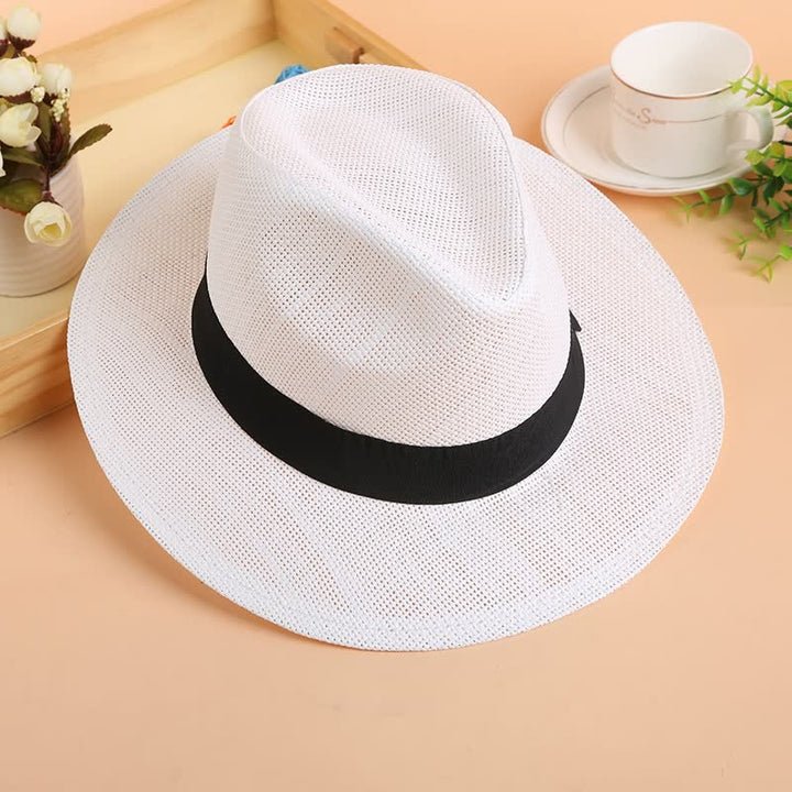 Weißer Fedora-Hut aus Stroh mit schwarzem Band auf Holztisch, stilvoller Sommerhut.