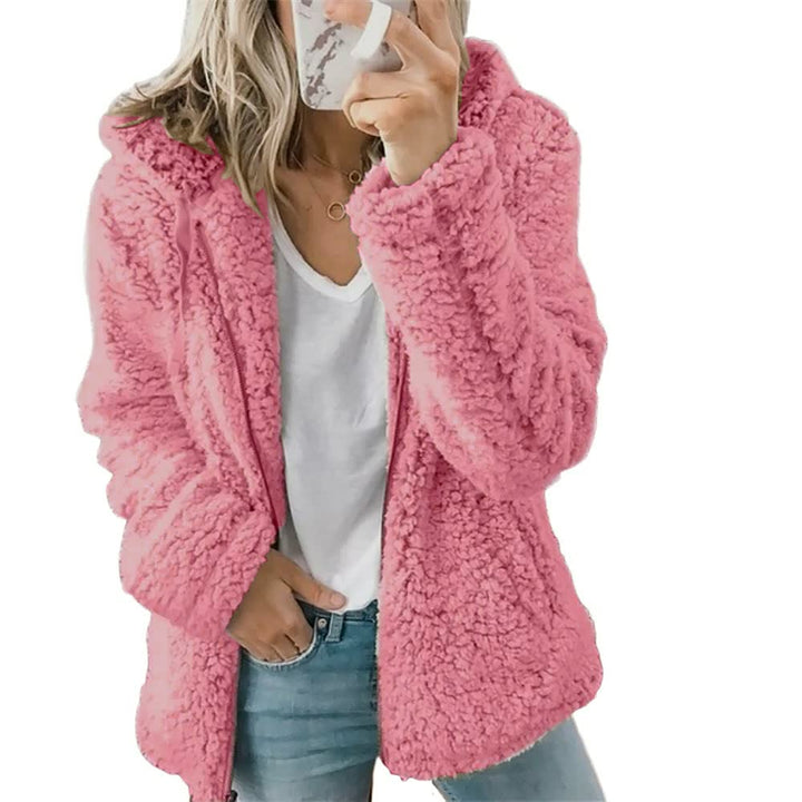 Frau in rosa Teddyfelljacke, weißem T-Shirt und Jeans, modische Winterbekleidung.