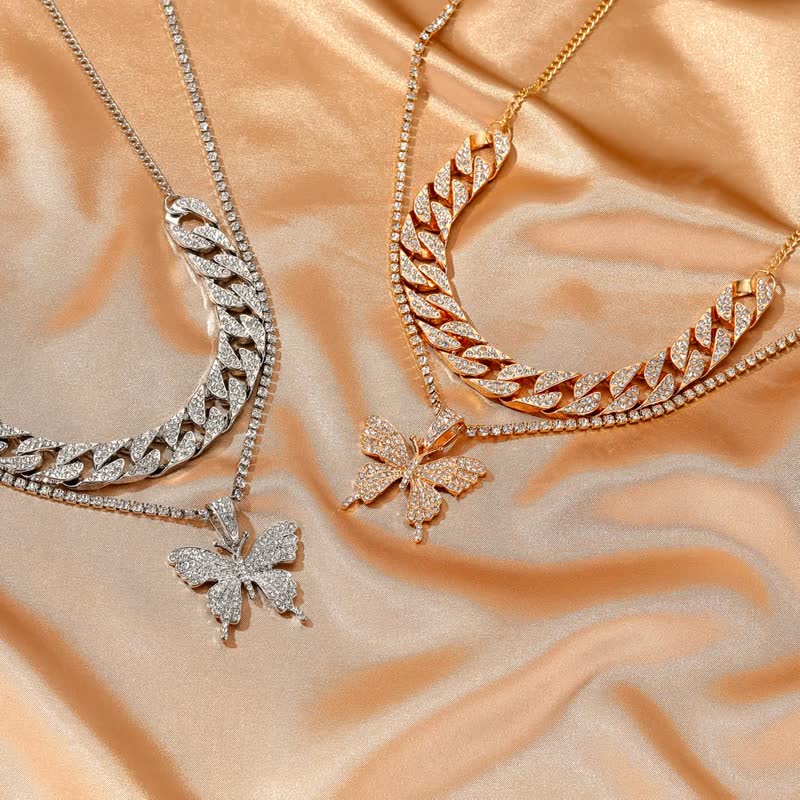 Zwei Schmetterlings-Halsketten, Gold und Silber, mit Strasssteinen auf seidigem Hintergrund.