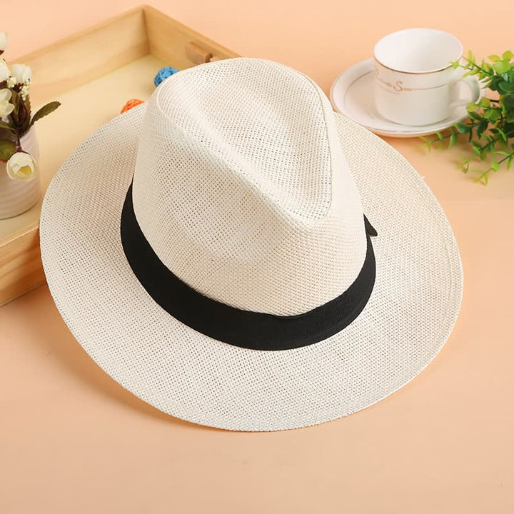 Weißer Panama-Hut aus Stroh mit schwarzem Band auf Holztisch, Sommermode-Accessoire.