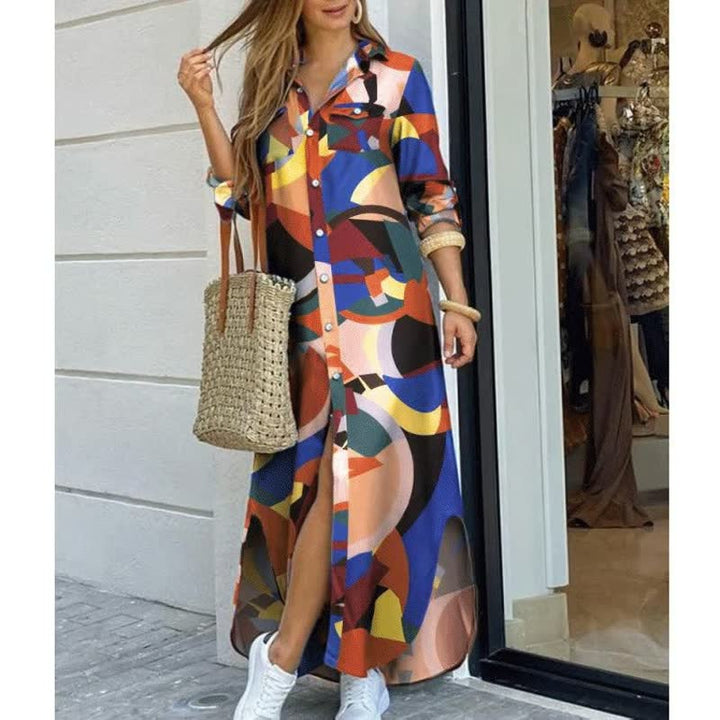 Frau in buntem Maxikleid mit geometrischem Muster, Strohtasche, weiße Sneaker, draußen.