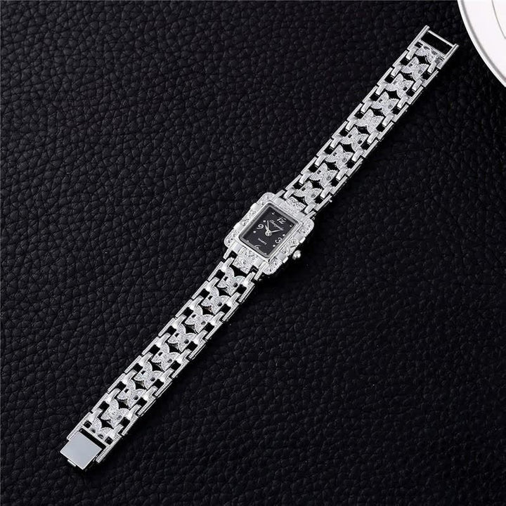 Luxus-Damenuhr mit silbernem Armband und schwarzem Zifferblatt auf schwarzem Hintergrund.