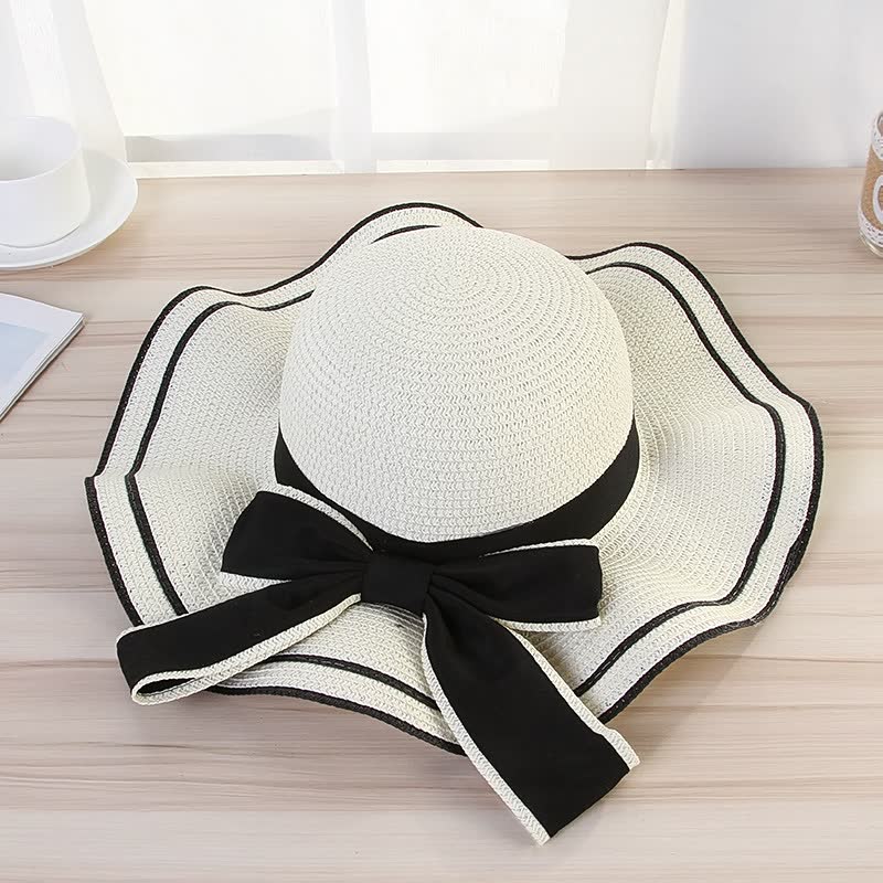 Weißer Damen-Sonnenhut mit schwarzer Schleife, elegantes Sommer-Accessoire aus Stroh.