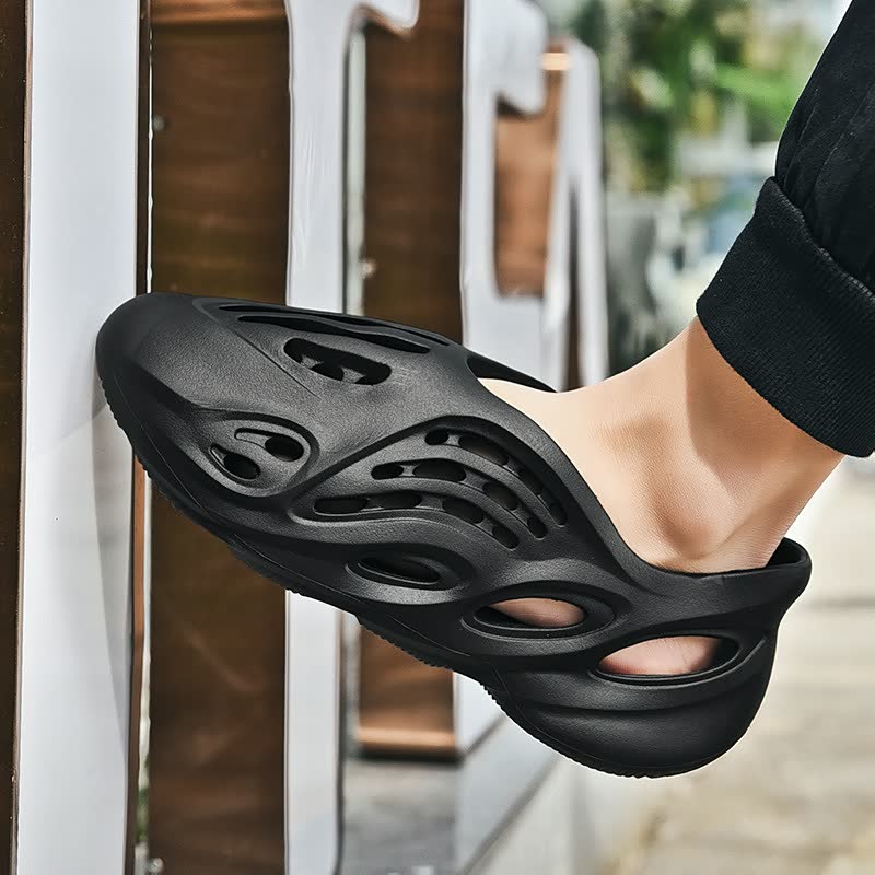 Schwarzer Sneaker mit Cut-Outs, atmungsaktiv, modern, Unisex, Freizeitschuh, Straßenszene.