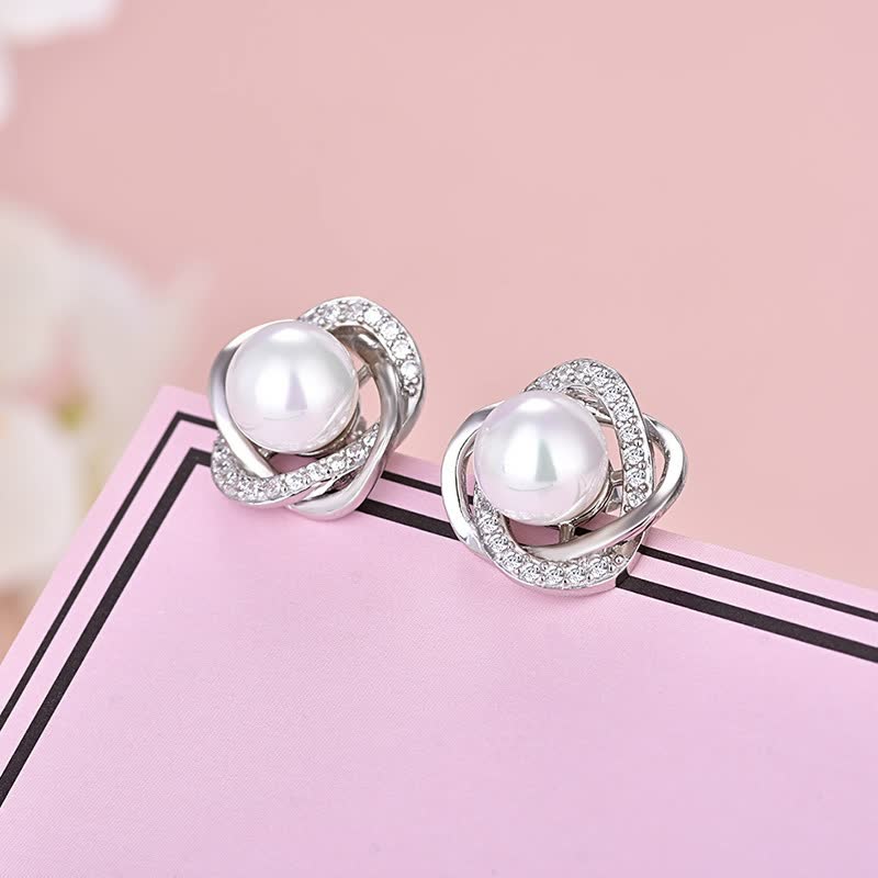 Silberne Ohrringe mit Perlen und Strasssteinen auf rosa Hintergrund, eleganter Schmuck.