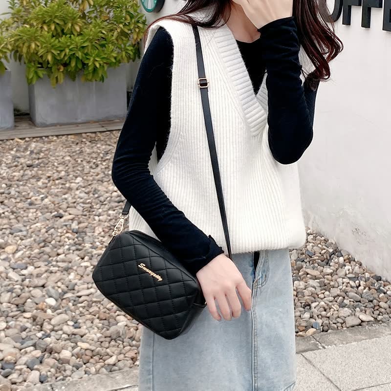Frau mit weißem Strickpullover, schwarzer Umhängetasche, Jeansrock, modisch, lässig.