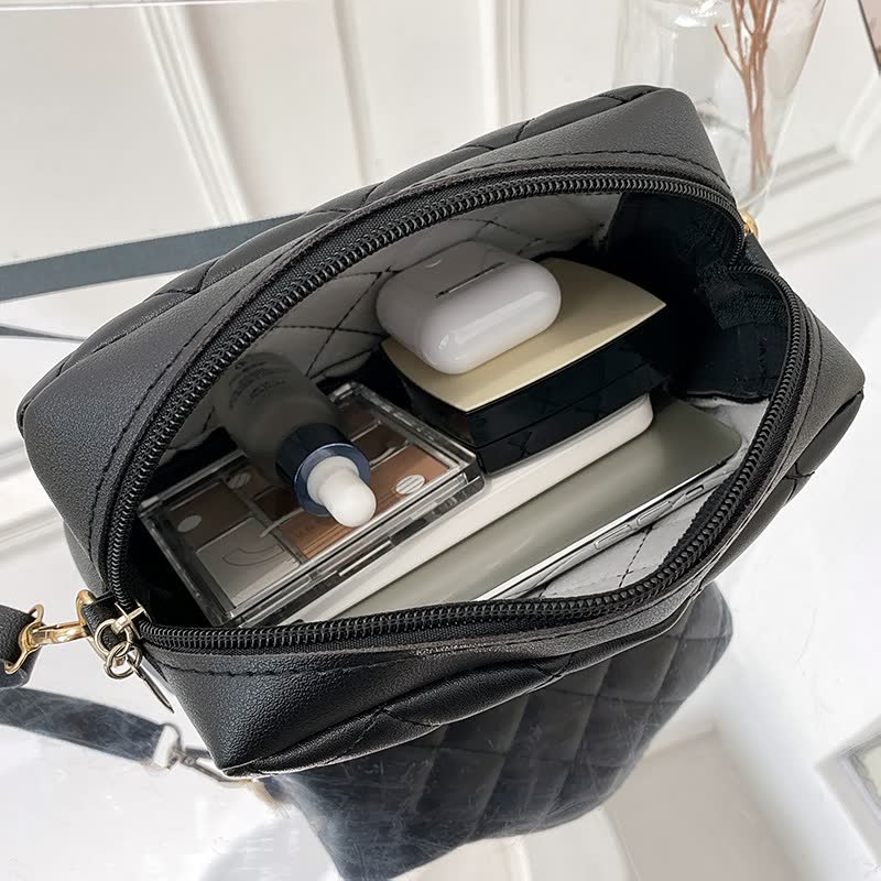 Schwarze gesteppte Handtasche mit Kosmetik und Elektronik, Reißverschluss, elegant, modern.