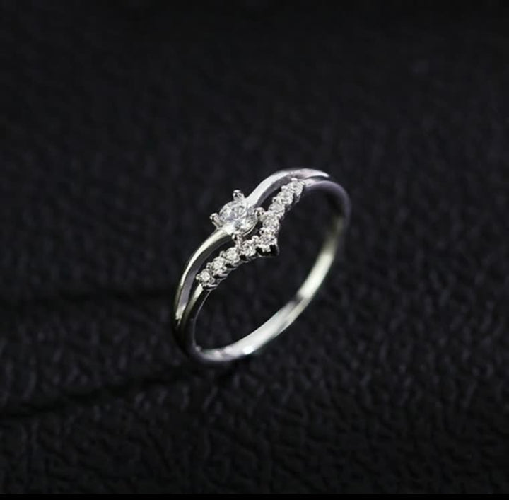 Silberner Diamantring mit geschwungenem Design auf schwarzem Hintergrund, eleganter Schmuck.