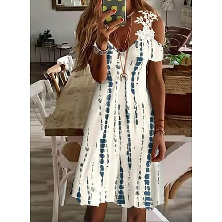 Frau in weißem Sommerkleid mit blauem Muster, Handy in der Hand, in modernem Esszimmer.