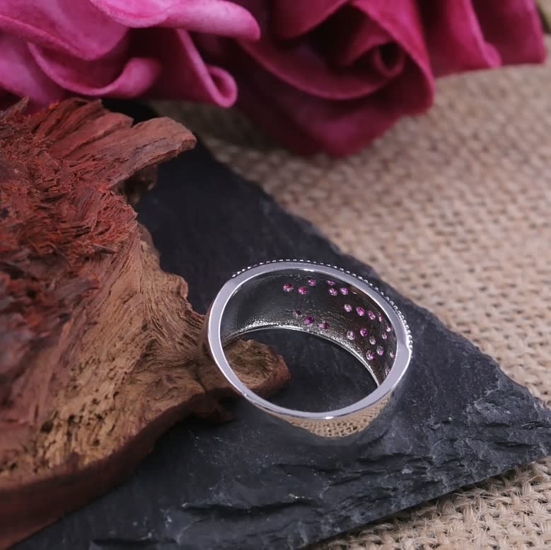 Silberring mit rosa Edelsteinen, Holz- und Schieferhintergrund, Schmuckdesign, elegant, modern.