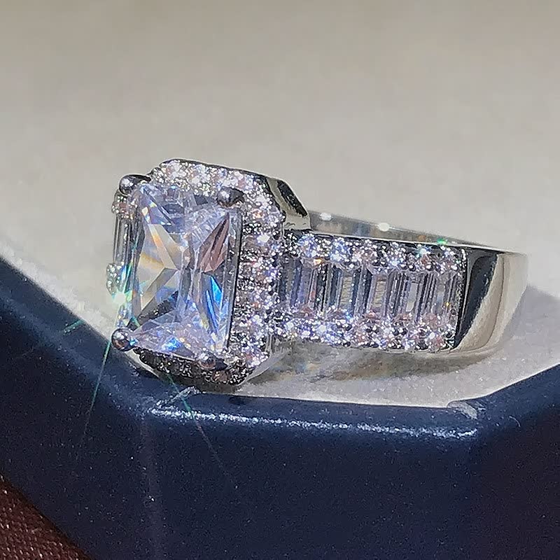 Silberner Verlobungsring mit quadratischem Diamant und Pavé-Fassung, funkelnd, elegant.