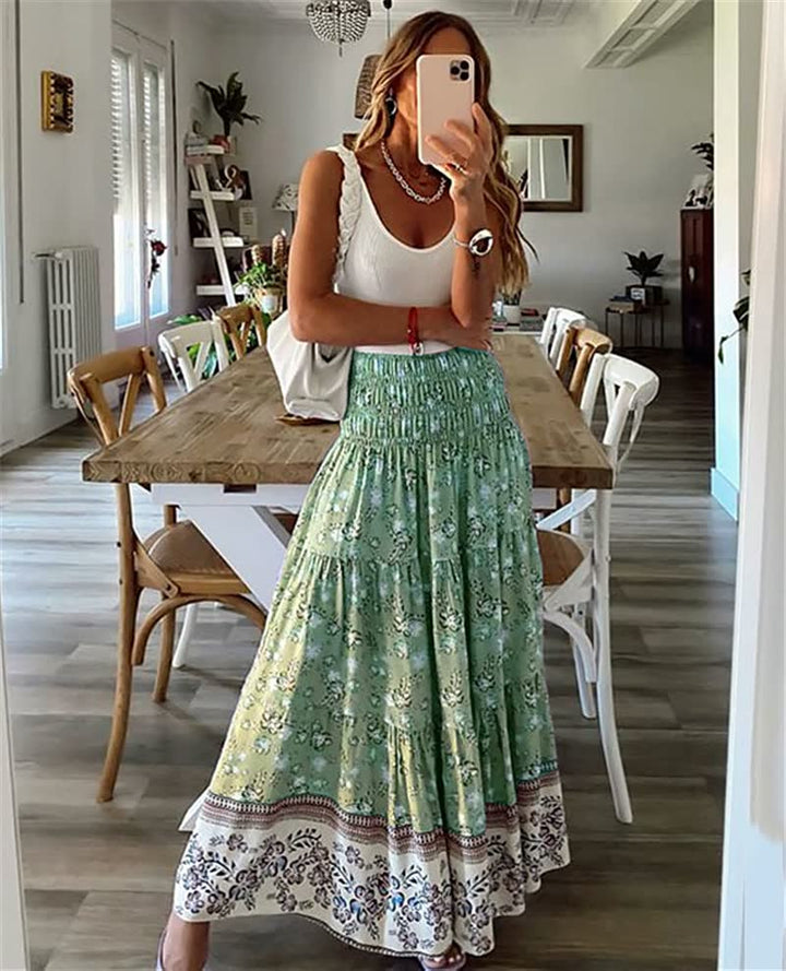 Frau in weißem Top und grünem Maxirock mit Blumenmuster, steht in modernem Esszimmer.