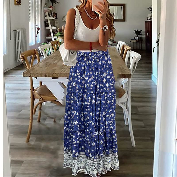 Frau in weißem Top und blauem Maxirock mit Blumenmuster in modernem Esszimmer.