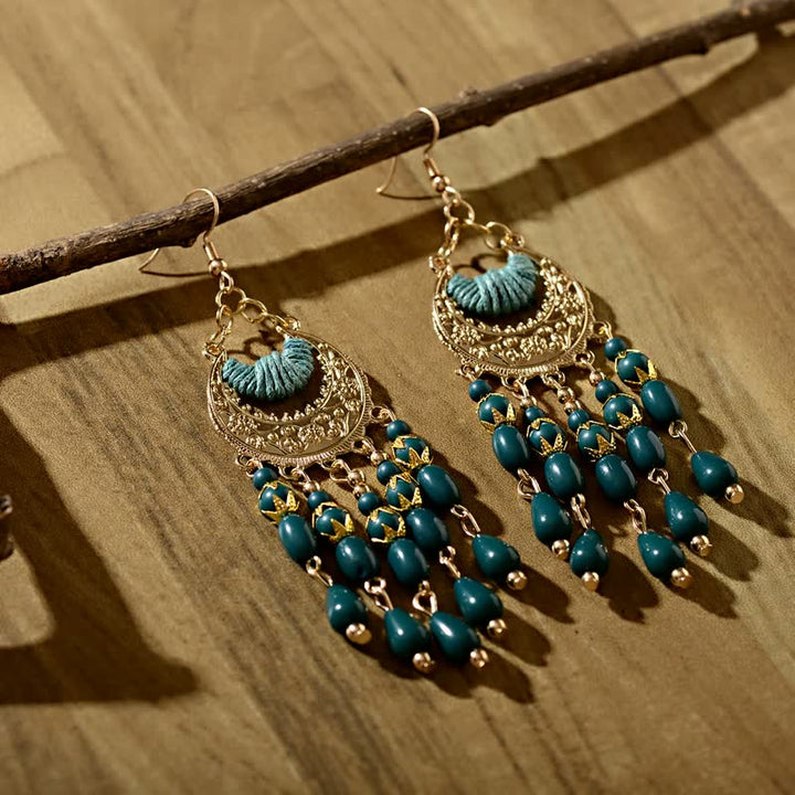 Goldene Ohrringe mit blauen Perlen, Boho-Stil, handgefertigt, hängend auf Holz, modisch.