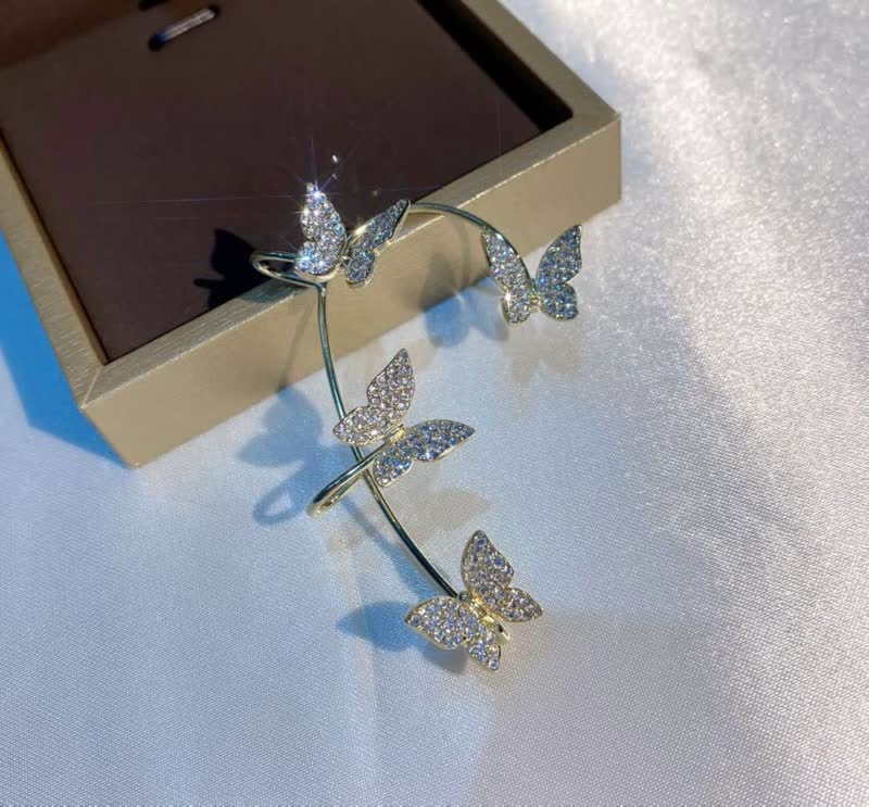 Goldene Schmetterlings-Haarspange mit Strasssteinen auf weißem Hintergrund, elegantes Accessoire.