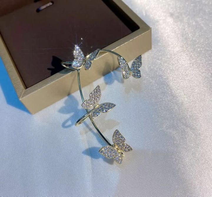Goldene Schmetterlings-Haarspange mit Strasssteinen auf weißem Hintergrund, elegantes Accessoire.