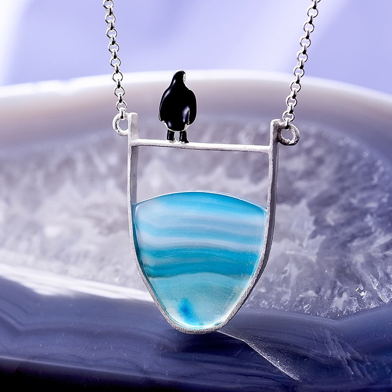 Silberkette mit blauem Achat-Anhänger und schwarzem Vogel, eleganter Schmuck für Damen.