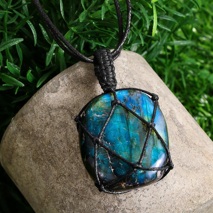 Blauer Opal-Anhänger mit schwarzem Lederband, handgefertigt, auf grünem Hintergrund.