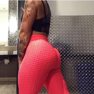Frau in roter Sportleggings im Fitnessstudio, muskulös, tätowiert, moderne Sportbekleidung.