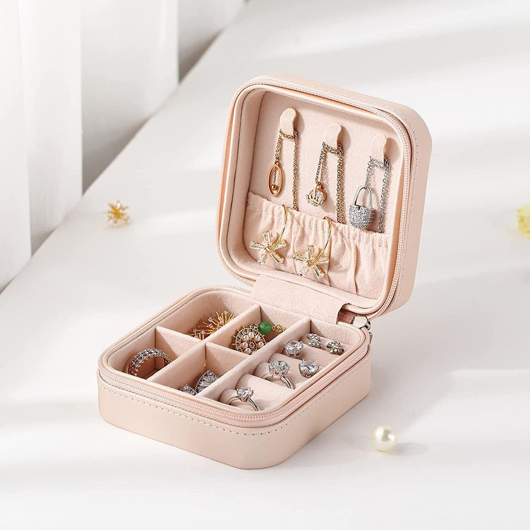 Rosa Schmuckkästchen aus Leder mit Fächern für Ringe und Ohrringe, ideal für Reisen.
