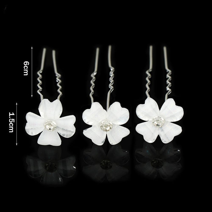 Drei weiße Haarspangen mit Blumen und Strasssteinen, 6 cm lang, auf schwarzem Hintergrund.