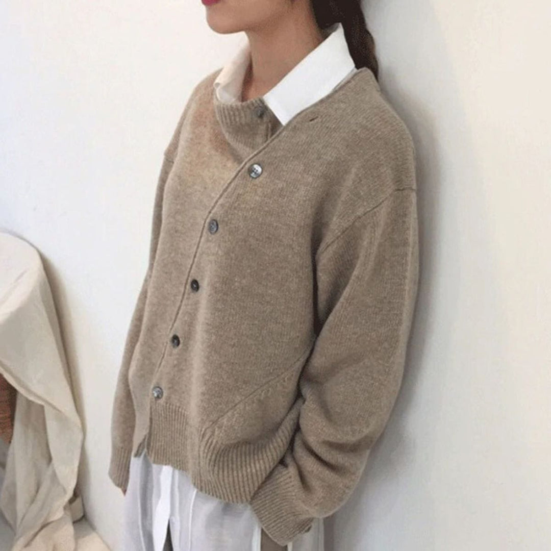 Frau trägt braunen Kaschmir-Cardigan mit Knopfleiste, über weißer Bluse, gemütlicher Herbstlook.