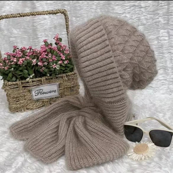 Beiges Strickmütze und Schal-Set aus Wolle, neben Sonnenbrille und Blumenkorb auf weißem Hintergrund.