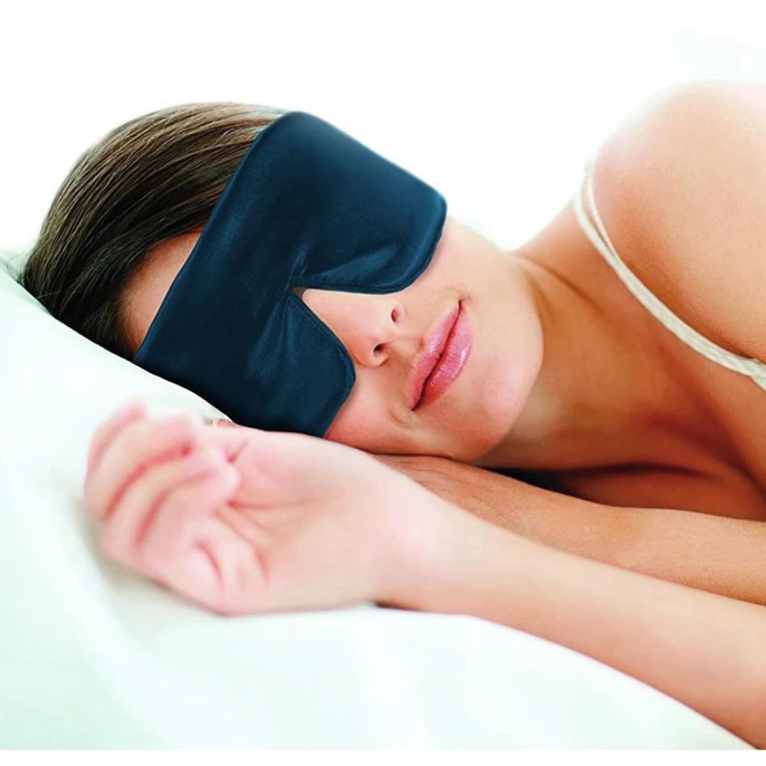 Frau mit schwarzer Schlafmaske aus Seide, liegend im Bett, Schlafzubehör, Entspannung.