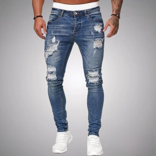 Středně modré roztrhané džíny s úzkým střihem, vyobrazené na modelovi v bílých teniskách zepředu. 3